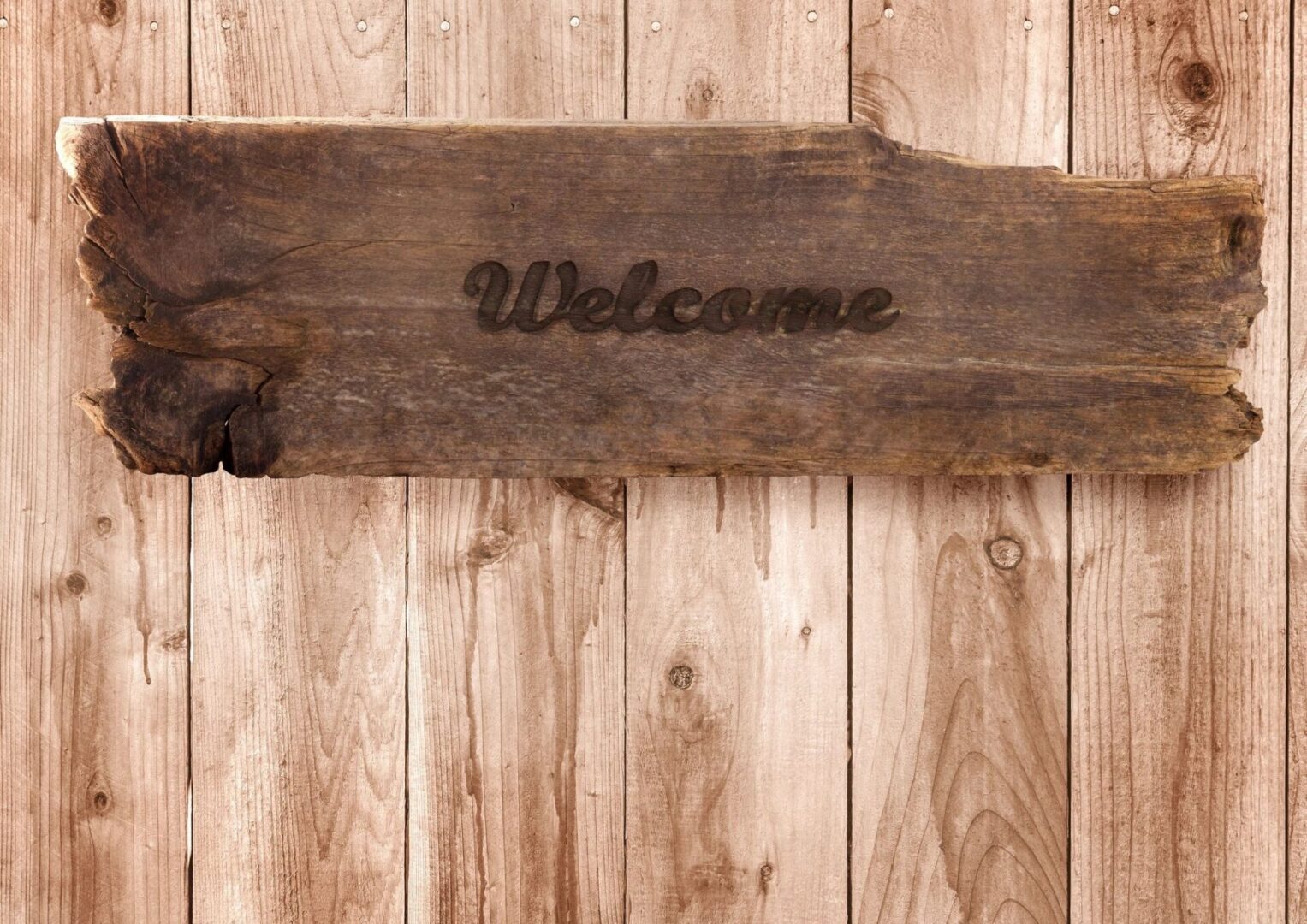 Welcome written on a wooden piece and hung on a wooden wall